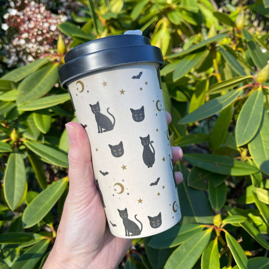 Travel coffee cup with black cats, bats and stars printed on it.