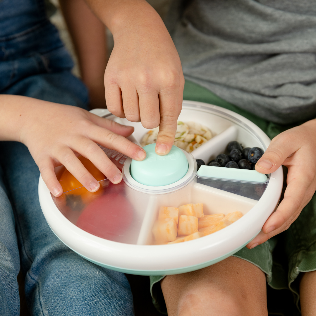 Child using a Gobe snack spinner lunch box in pale blue and white.