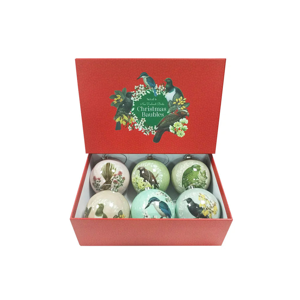 Six round Christmas baubles each in a light pastel colour. Each bauble features a native NZ bird perched on a native NZ flower. Placed in a red cardboard gift box.
