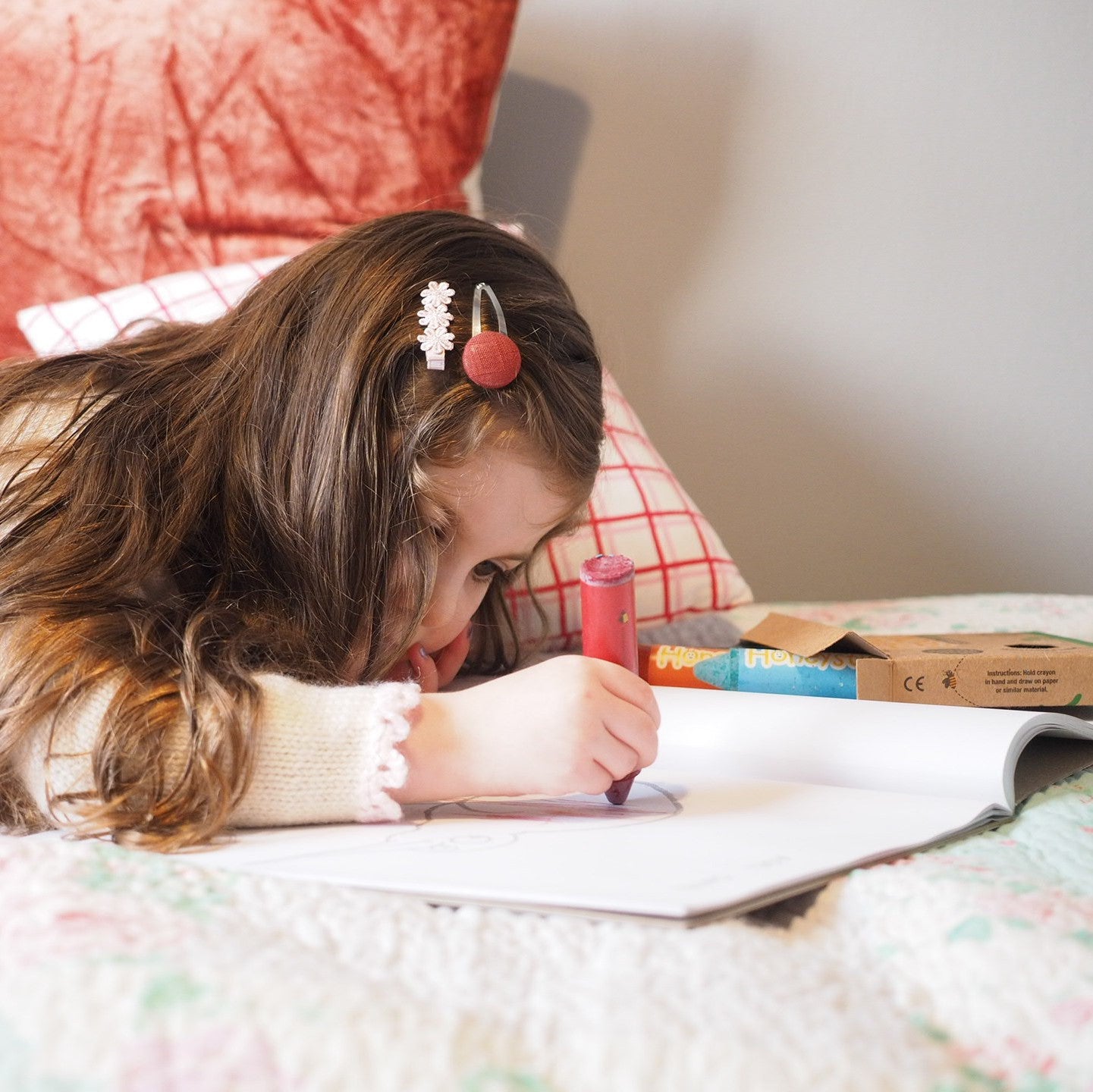 Child drawing with large red crayon.