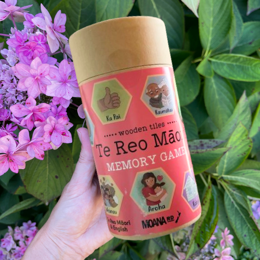 Women's hand holding cardboard tube with a Te Reo Maori Memory Game inside.