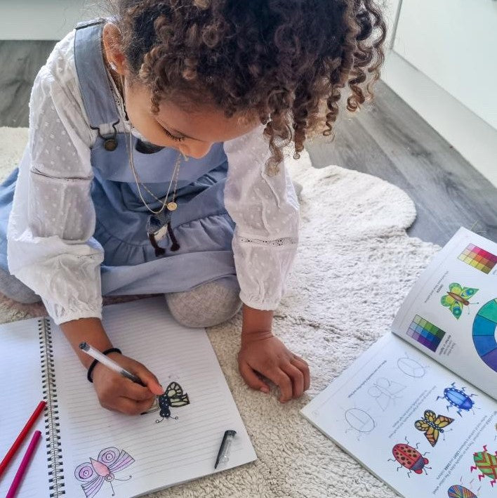 Child drawing using an art guide book.