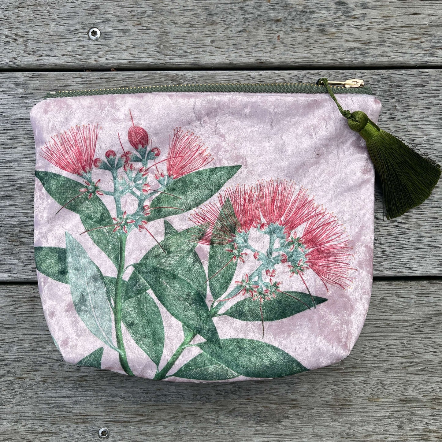 Pale pink velvet cosmetic bag with green tassel and a pohutukawa flower print.