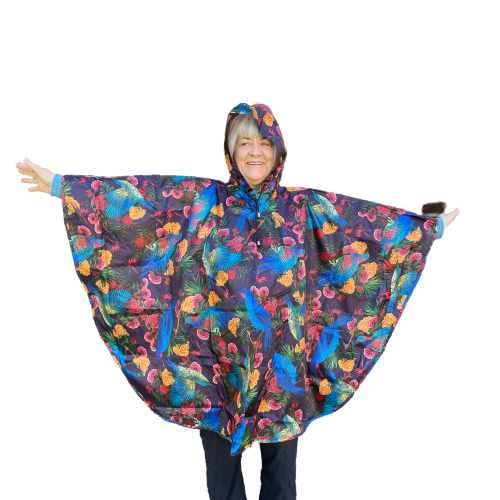 Woman wearing a rain poncho with birds and flower print on a deep aubergine purple background.