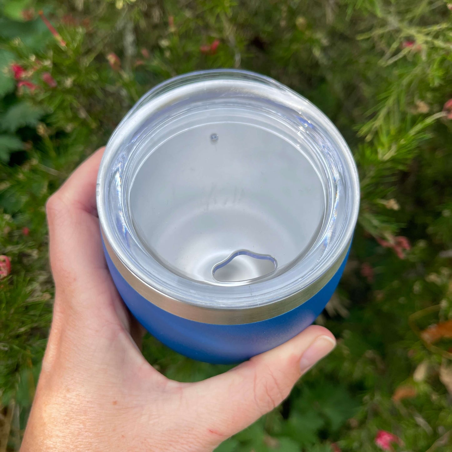 Birds eye view of a stainless coffee mug featuring the clear plastic sipper top.