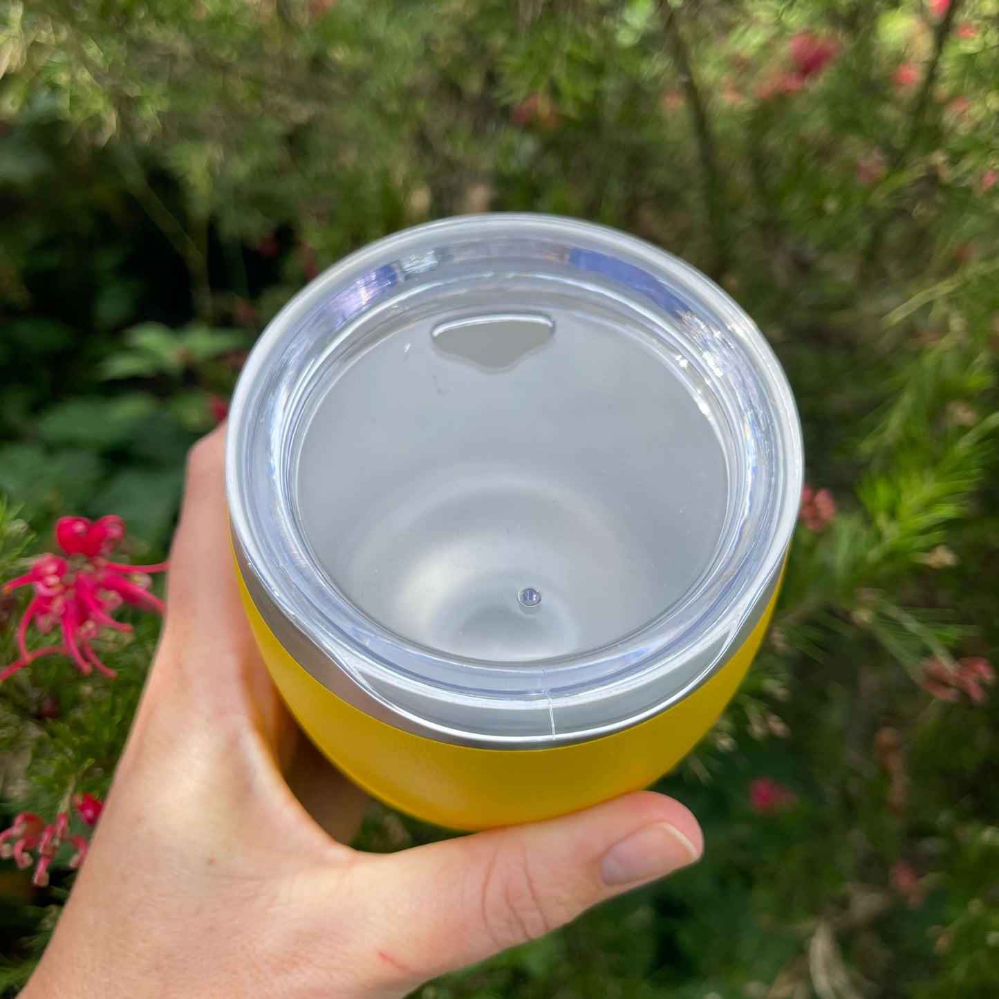 Birds eye view of a stainless coffee mug featuring the clear plastic sipper top.