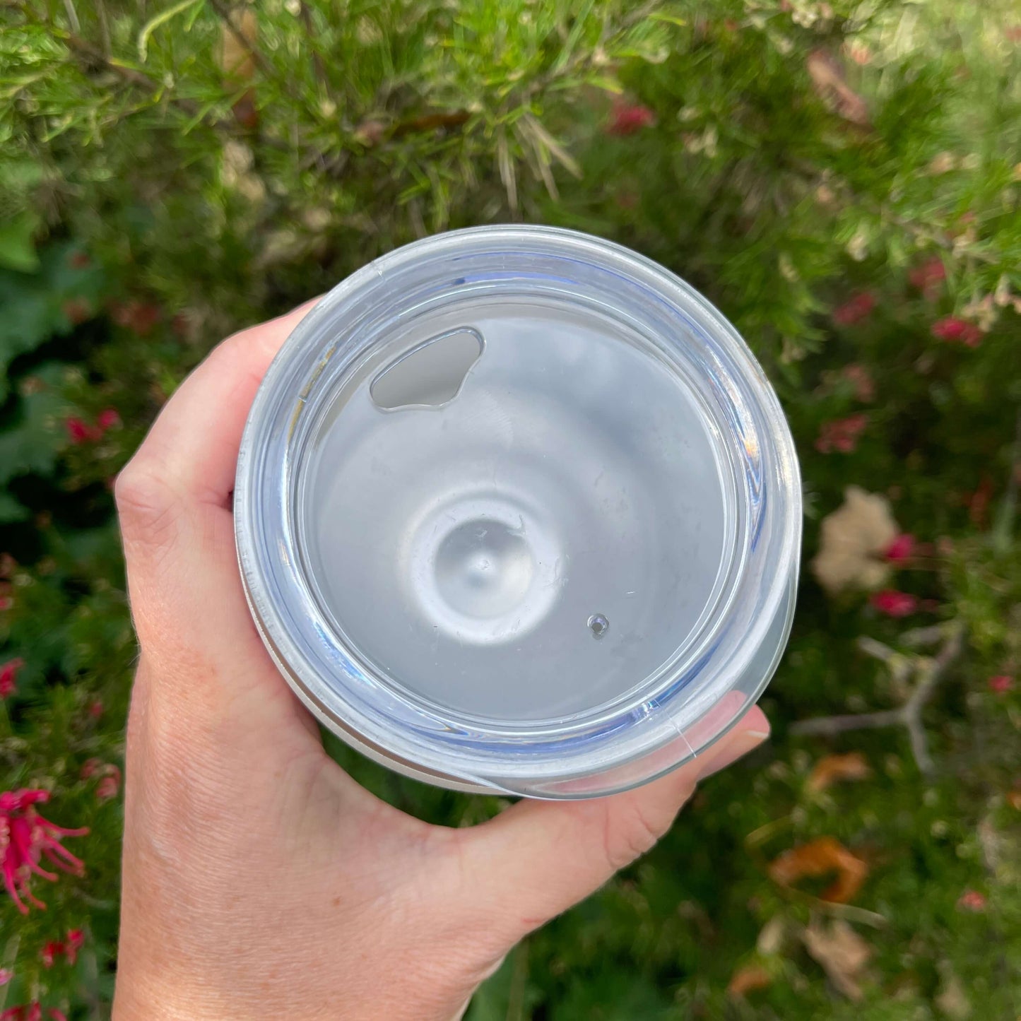 Birds eye view of a stainless coffee mug featuring the clear plastic sipper top.