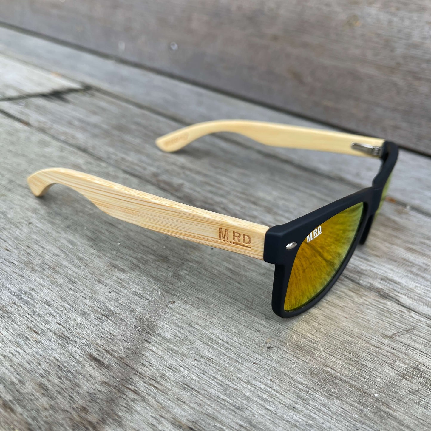 Sunglasses with wooden arms, black frames and reflective lenses.