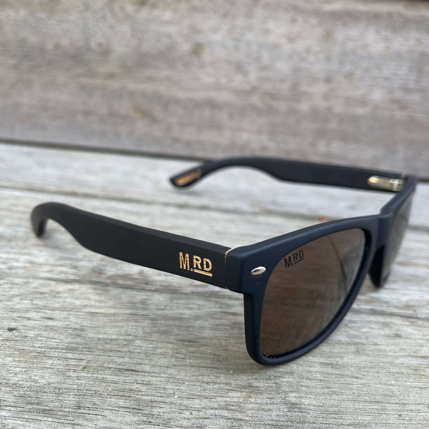Sunglasses with dark wooden arms, black frames and dark lenses.
