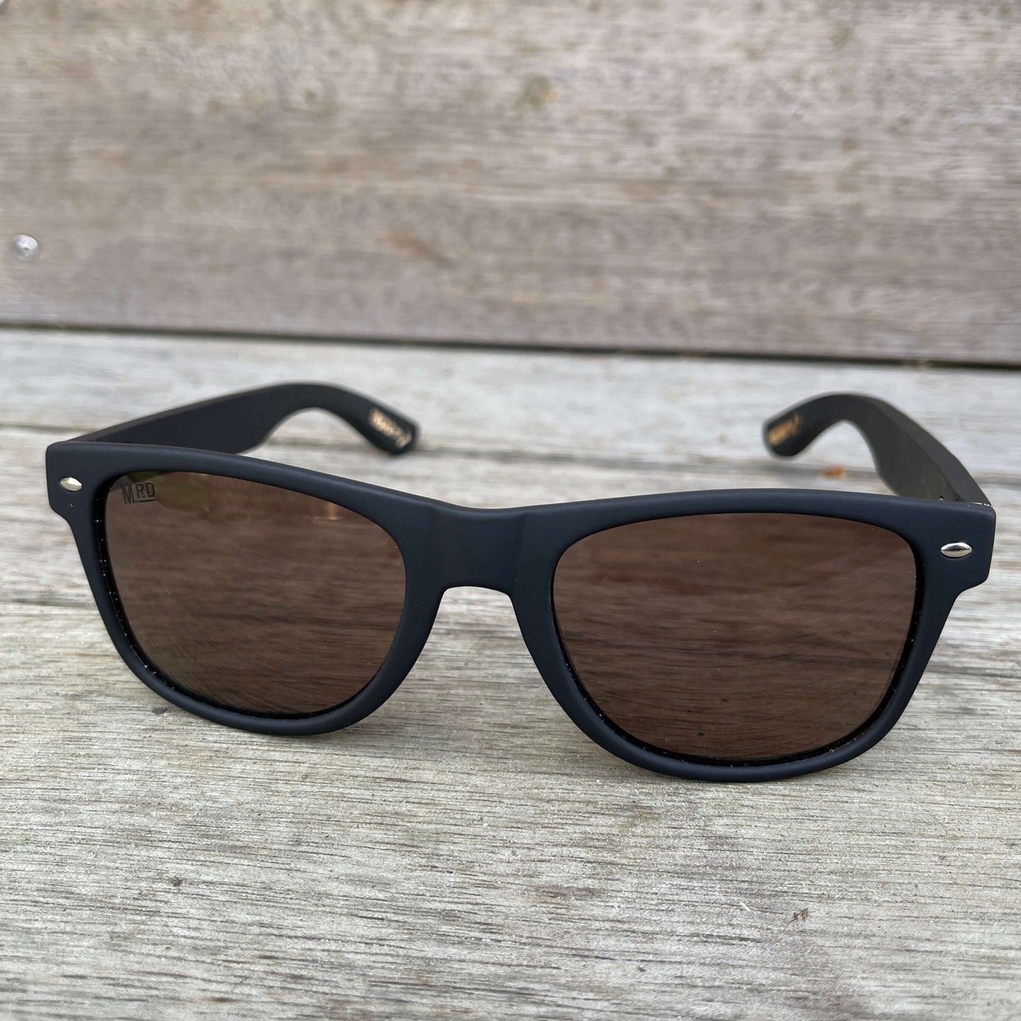 Sunglasses with dark wooden arms, black frames and dark lenses.