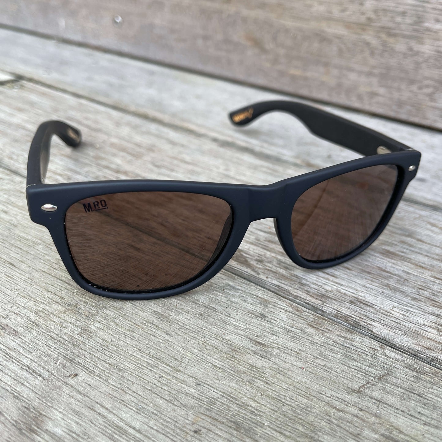 Sunglasses with dark wooden arms, black frames and dark lenses.