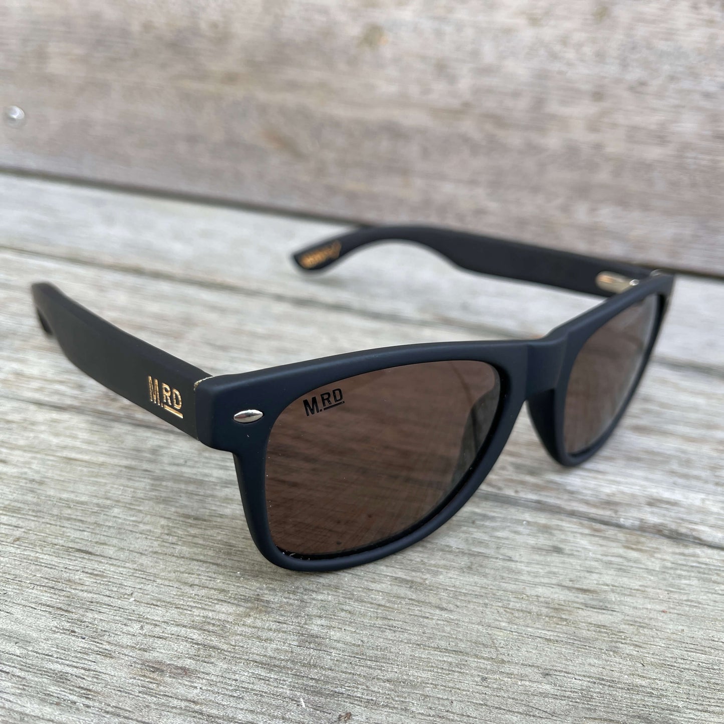 Sunglasses with dark wooden arms, black frames and dark lenses.