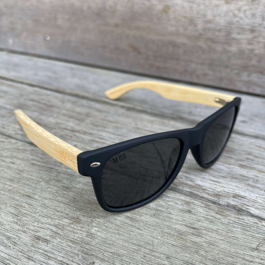 Sunglasses with wooden arms, black frames and dark lenses.