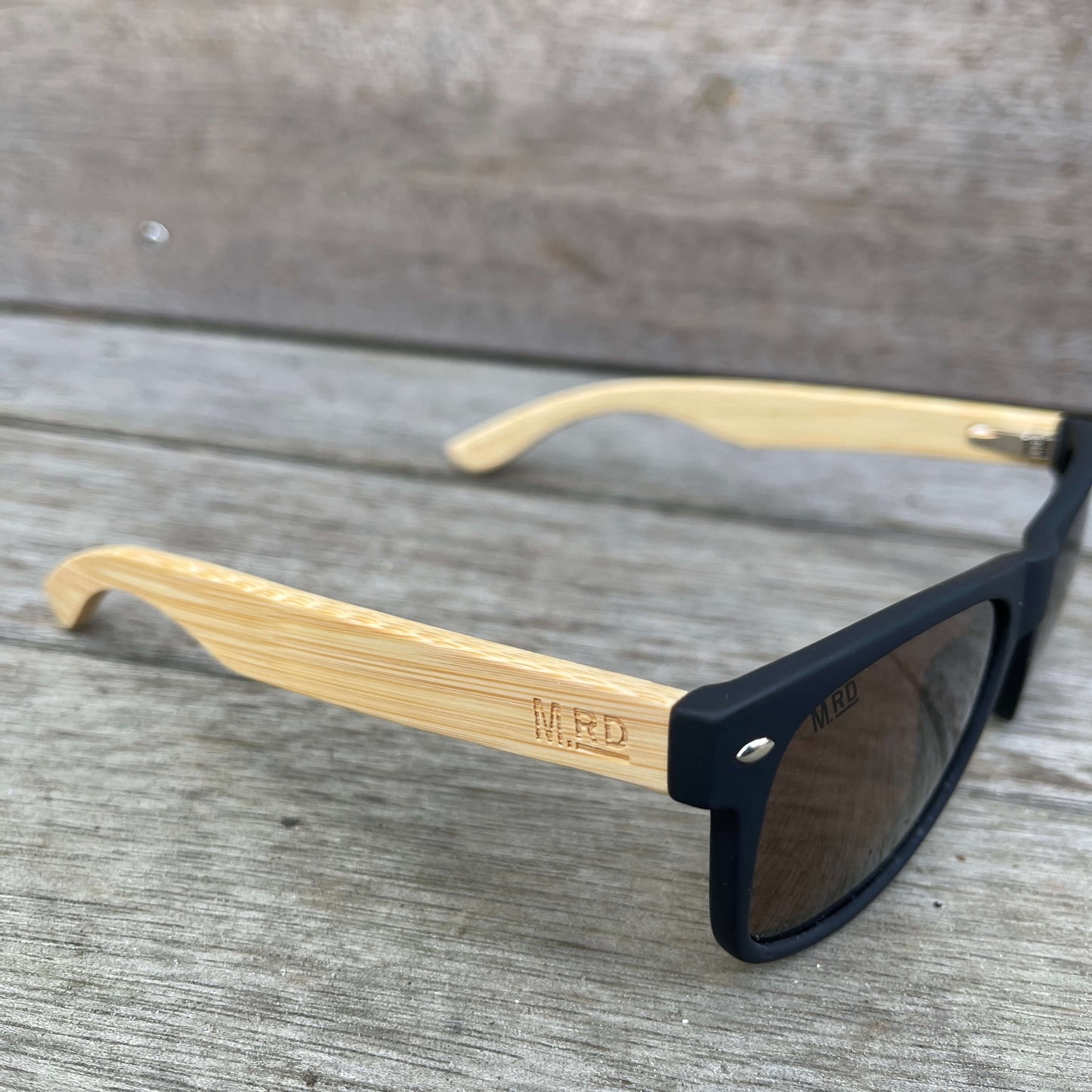 Sunglasses with wooden arms, black frames and brown lenses.