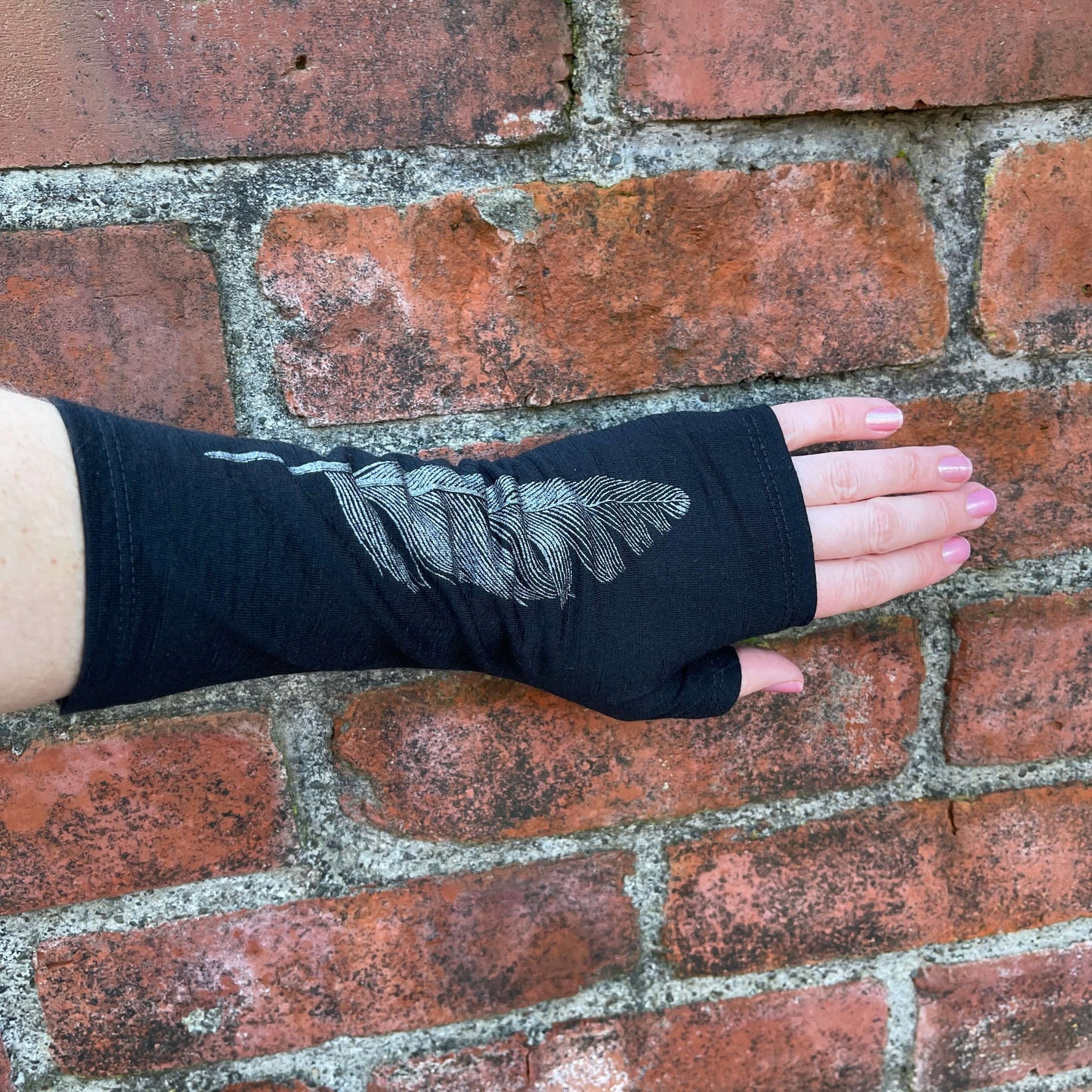 Fingerless merino gloves in black with silver feather print.