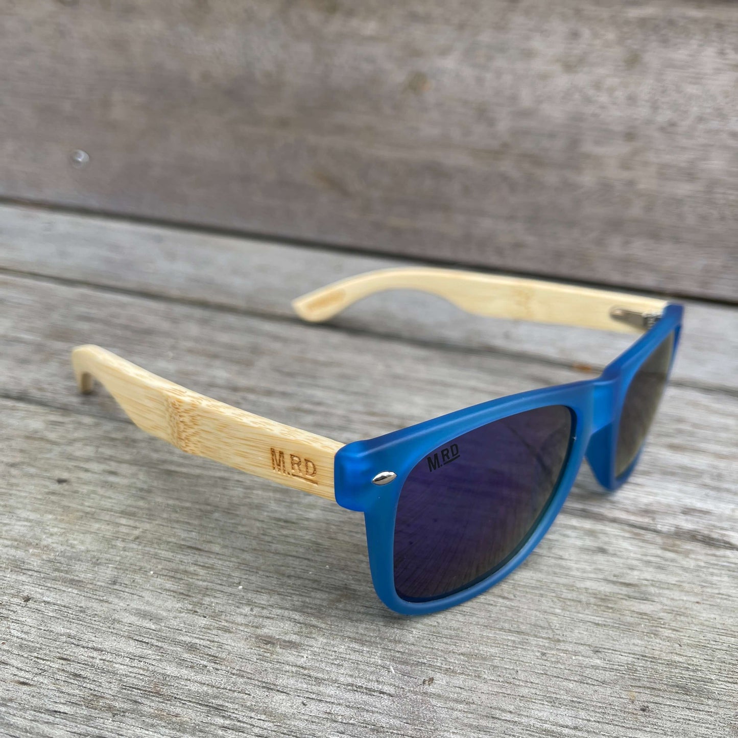Sunglasses with wooden arms, blue frames and blue reflective lenses.