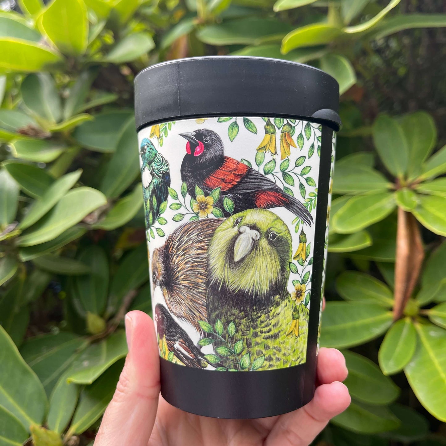Black reusable coffee cup wrapped with beautiful drawings of New Zealand birds.