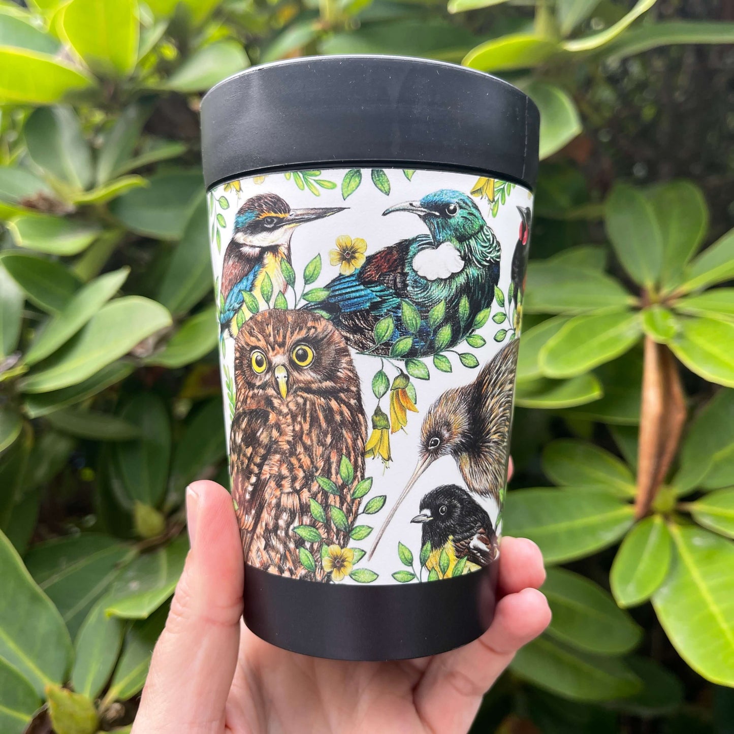 Black reusable coffee cup wrapped with beautiful drawings of New Zealand birds.
