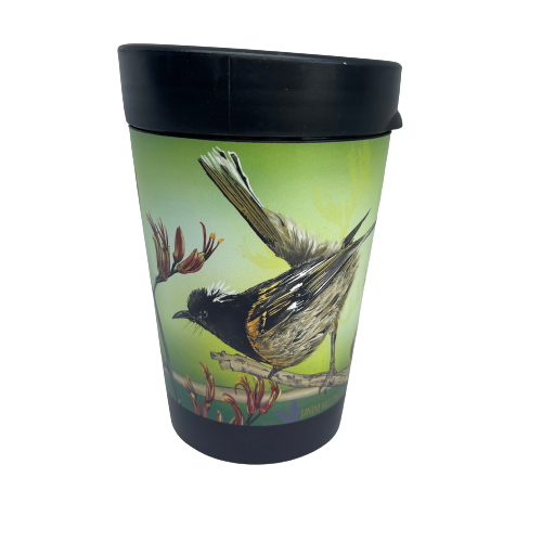 Black reusable coffee cup with Hihi birds and Flax flowers on a green background.