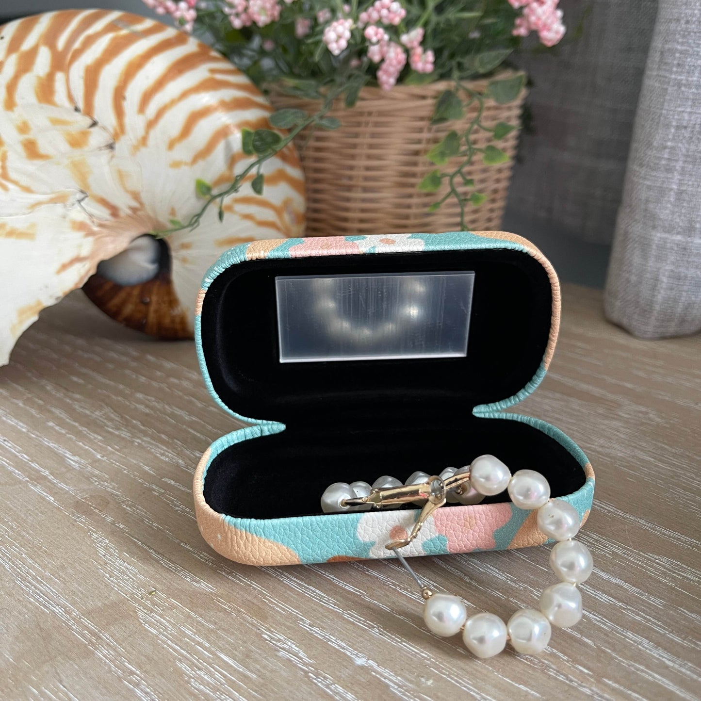 Small trinket case open with mirror and pearl earrings.