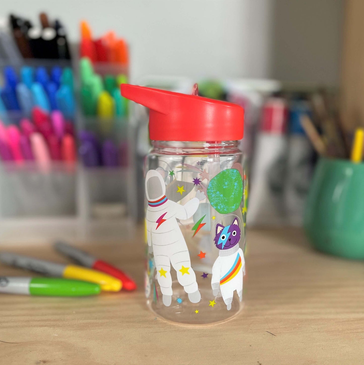 Kids drink bottle with spaceships and astronauts printed on it. Features a red lid with clear sipping tube.