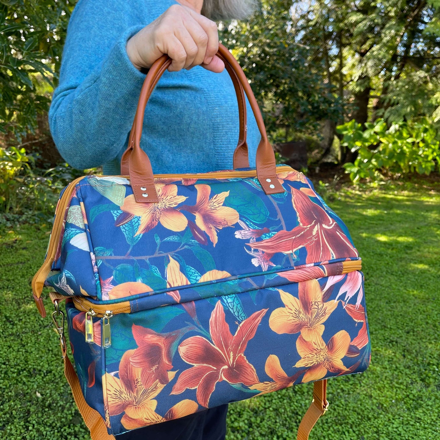 Women holding a large cooler bag which is a navy blue with orange flowers.