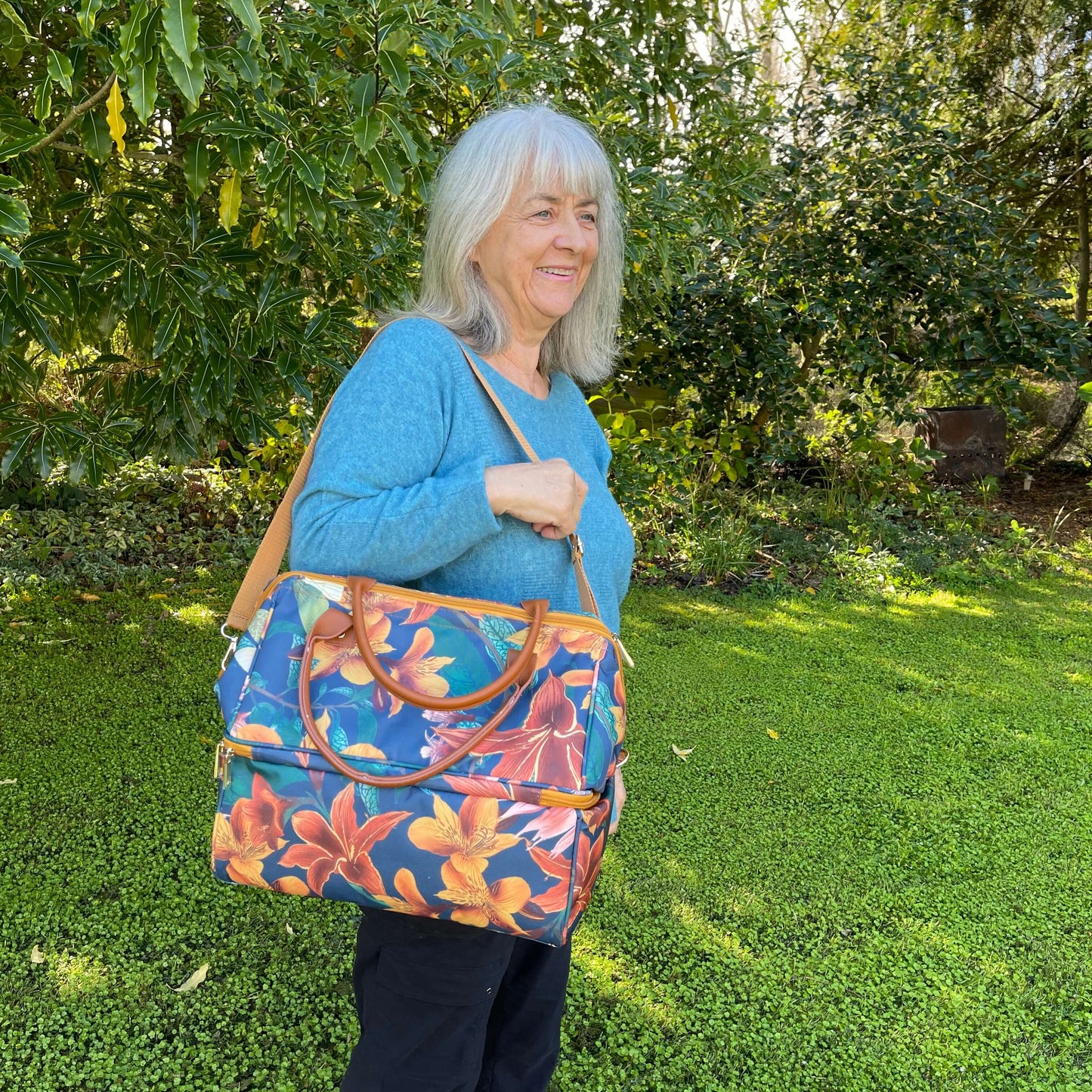 Women holding a large cooler bag which is a navy blue with orange flowers.