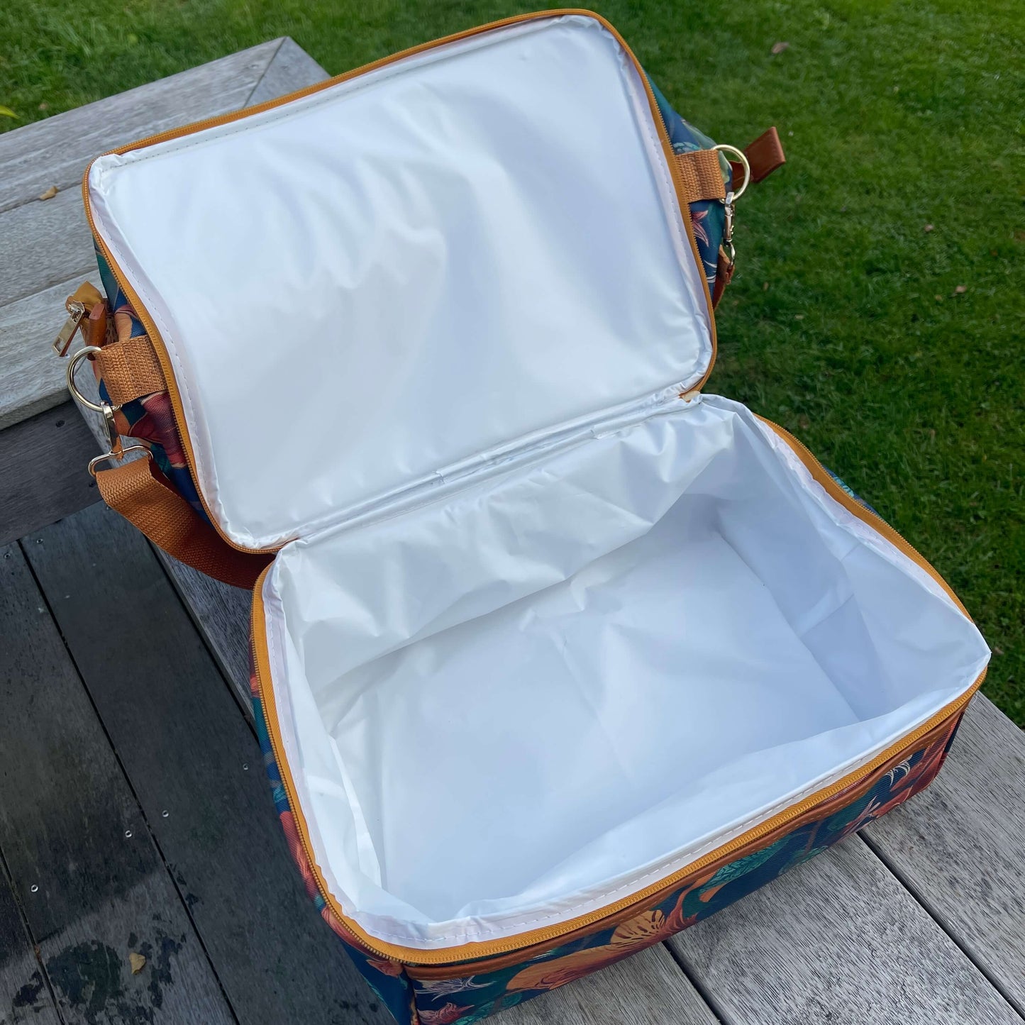 Large fabric cooler bag sitting on a deck opened up to show white lining.