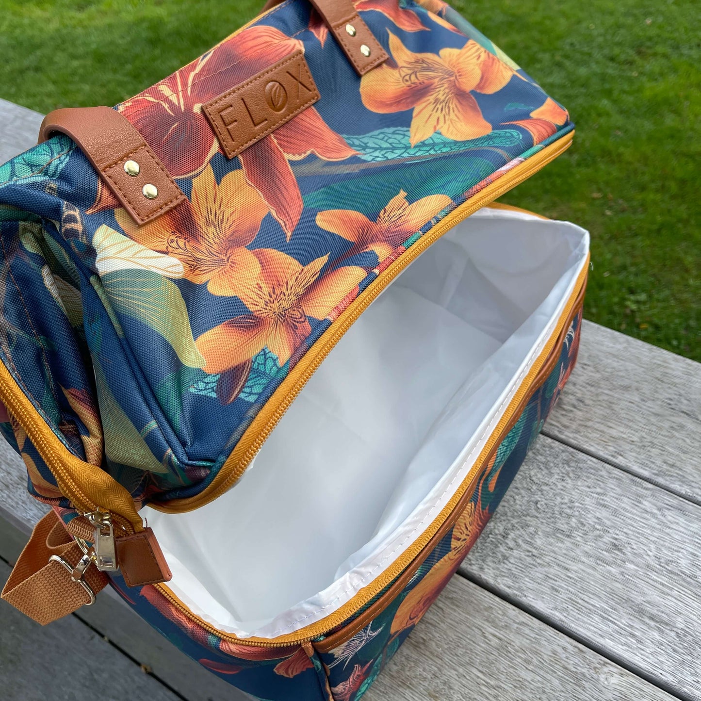 Large floral cooler bag sitting on a deck slightly open.