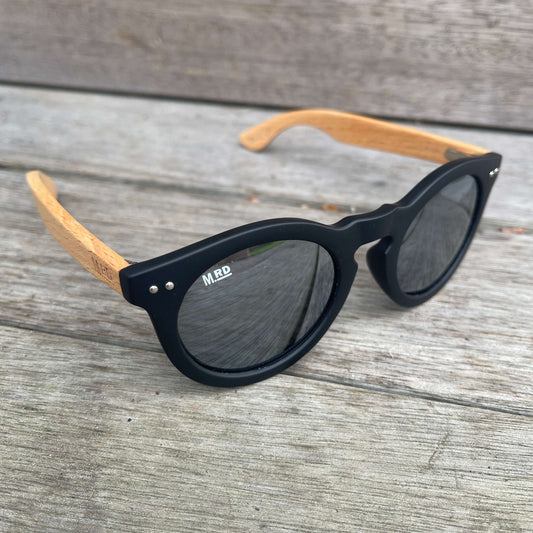 Womens sunglasses with black frames, wooden arms and silver reflective lenses in a Grace Kelly style.