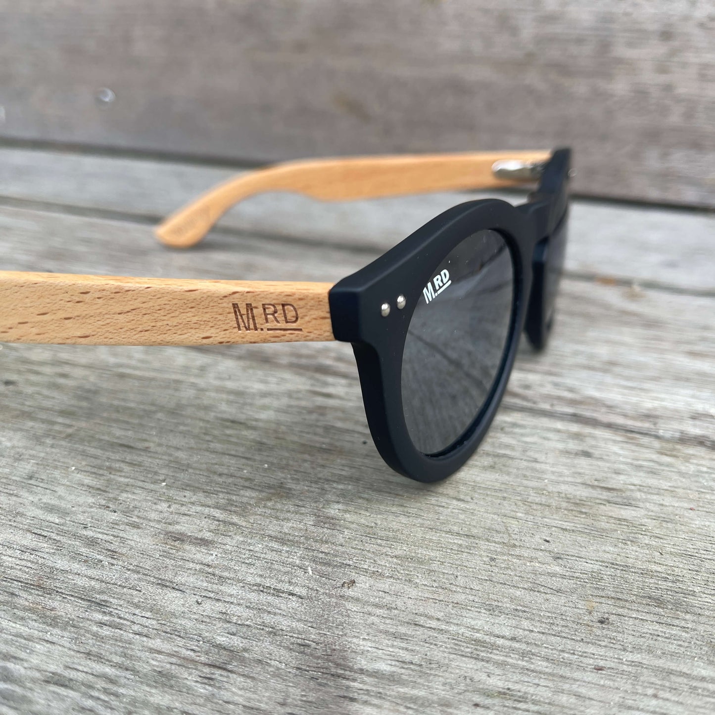 Womens sunglasses with black frames, wooden arms and silver reflective lenses in a Grace Kelly style.