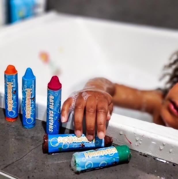 Child in a bath playing with bath crayons.