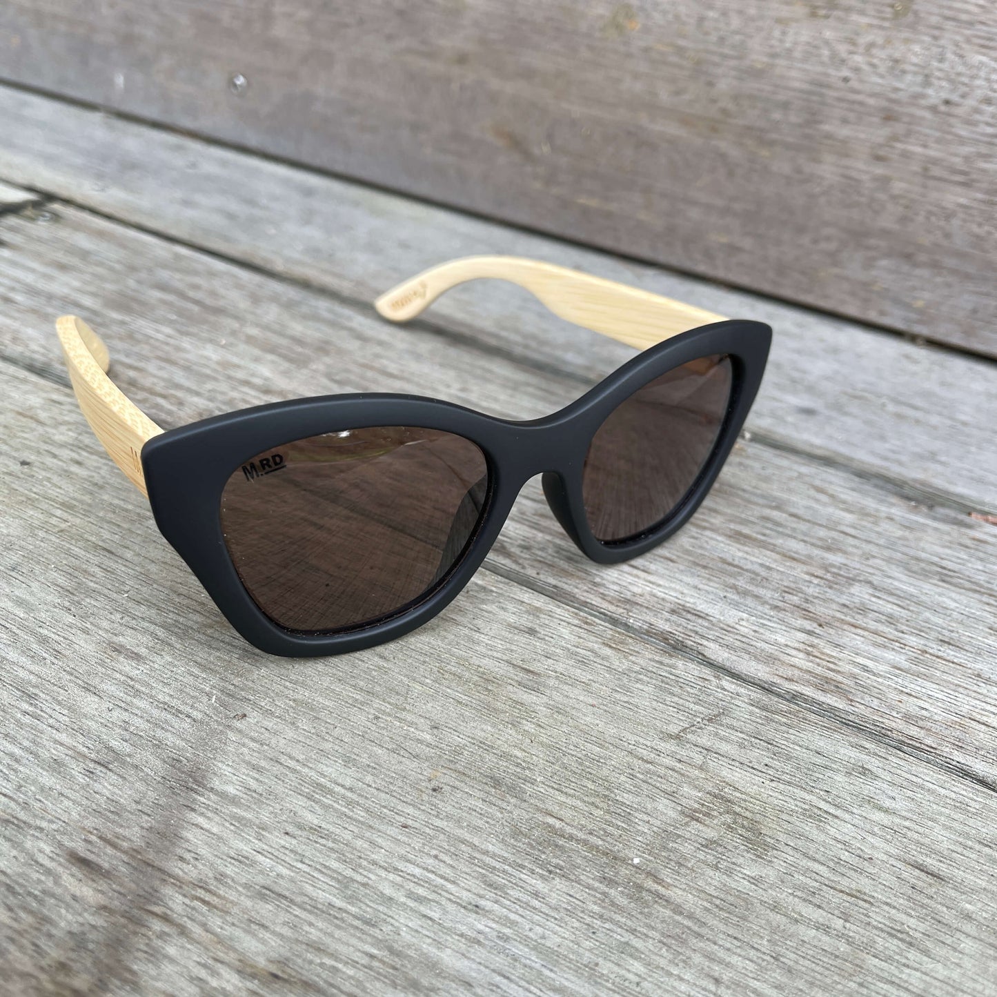 Womens sunglasses with black frames and wooden arms, in an Audrey Hepburn style.