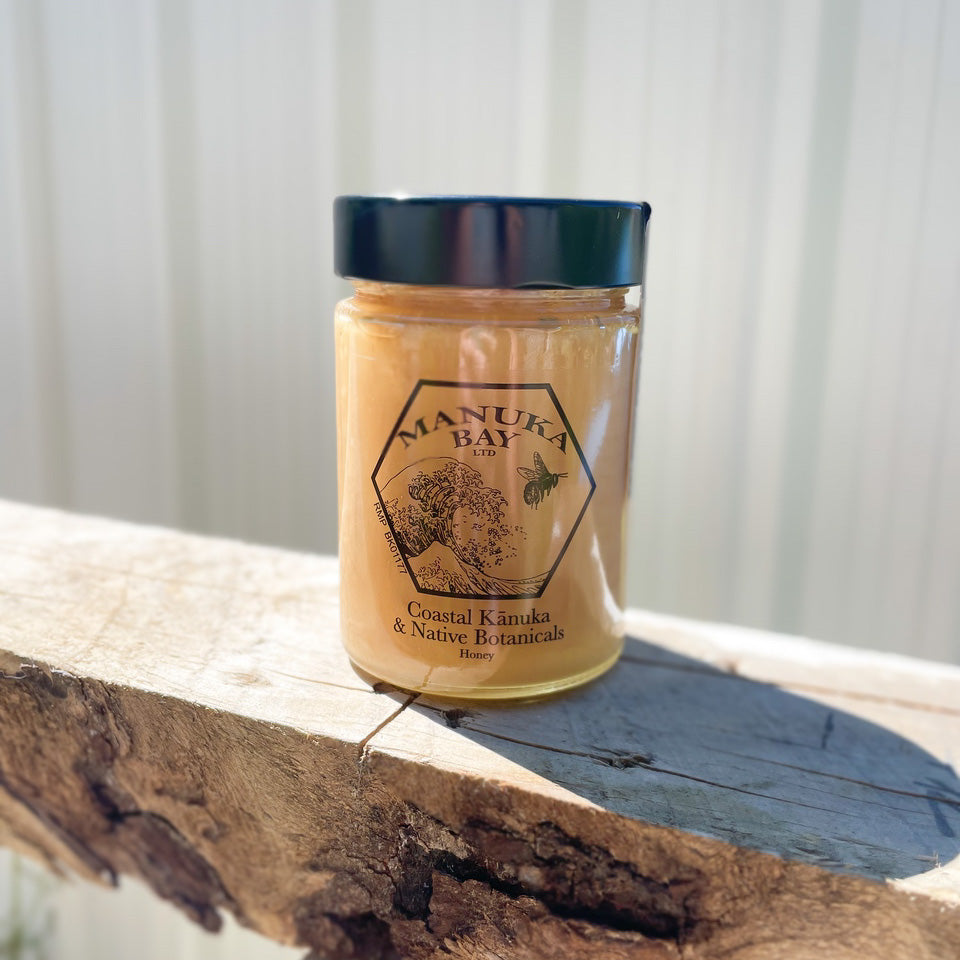 Glass jar with black lid filled with Manuka Bay Kanuka Honey.