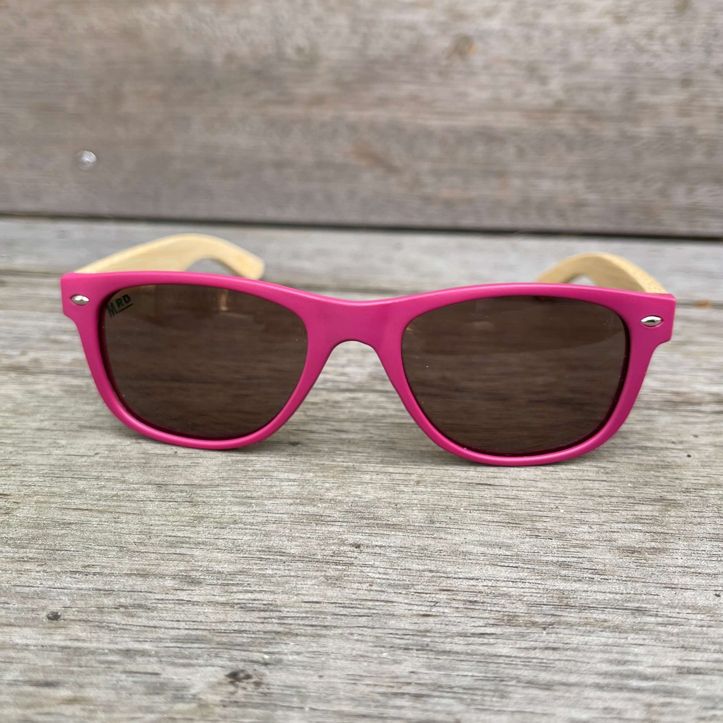 Kids sunglasses with pink frame and wooden arms.