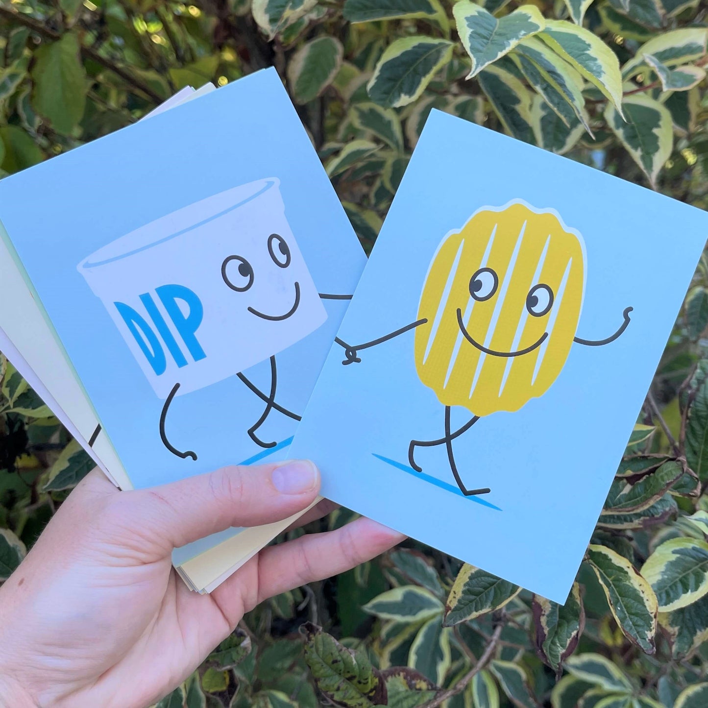 Women's hand holding chip & dip cards for a New Zealand themed memory game.