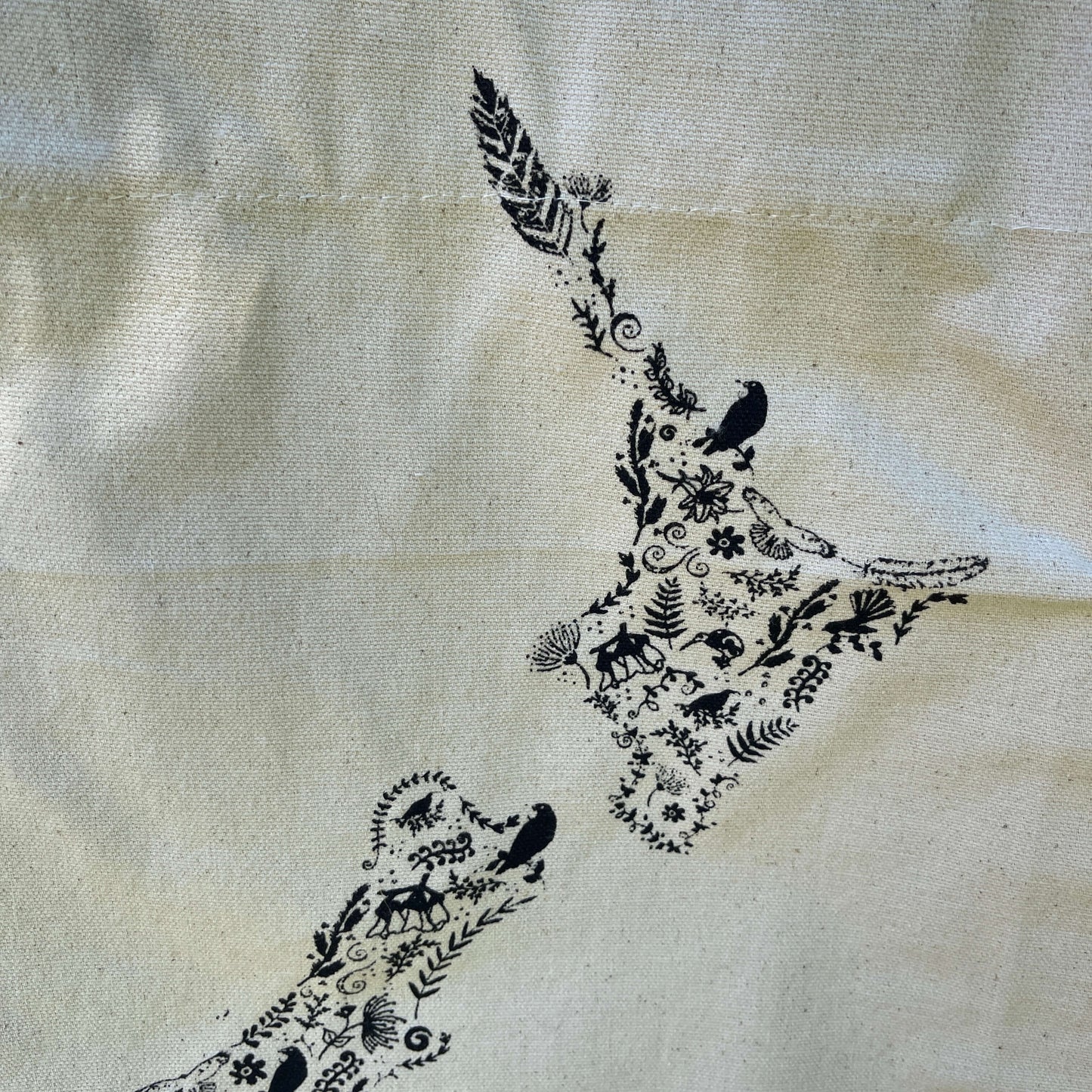 Canvas tote bag with black floral map of NZ printed on it.