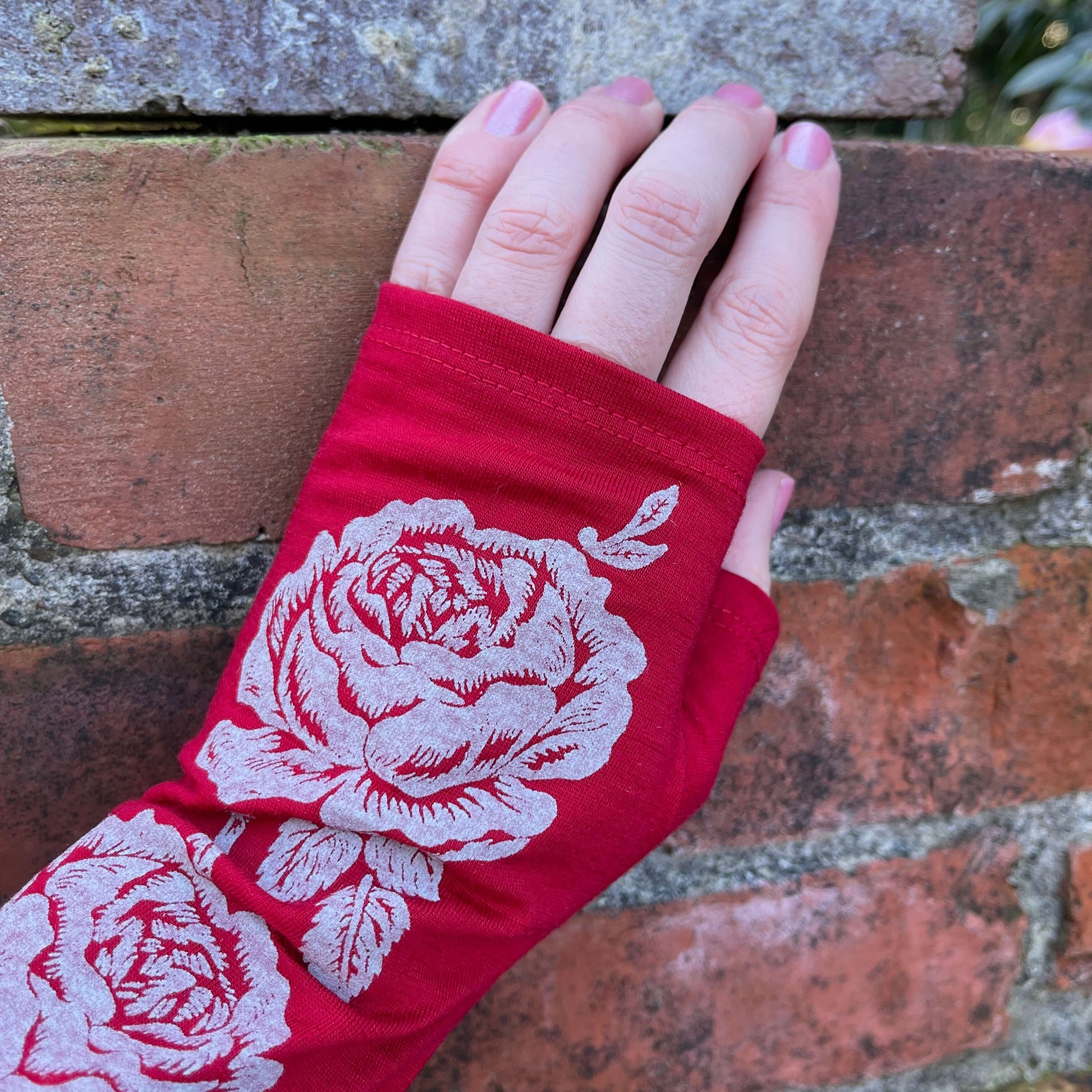 Fingerless merino gloves in red with white rose print.