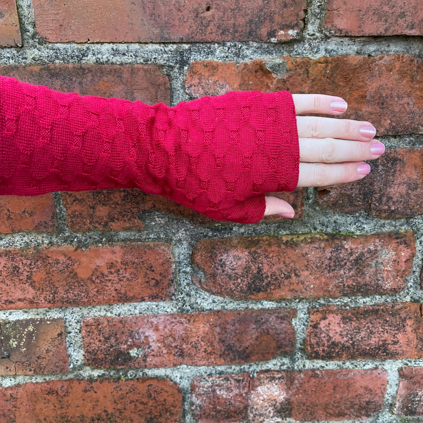 Fingerless merino gloves in red textured knit.