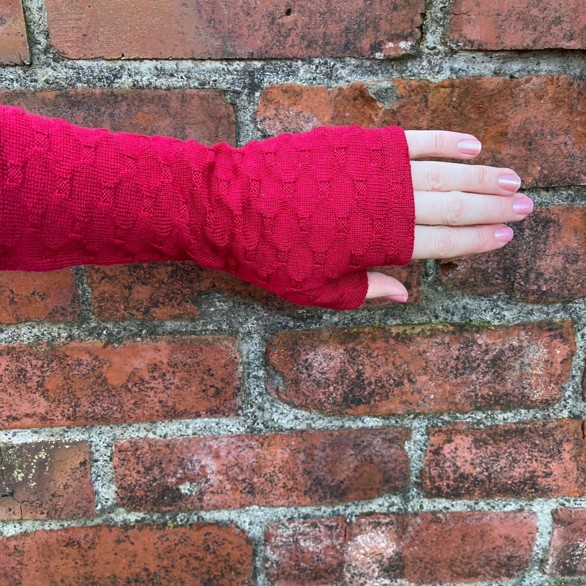 Fingerless merino gloves in red textured knit.