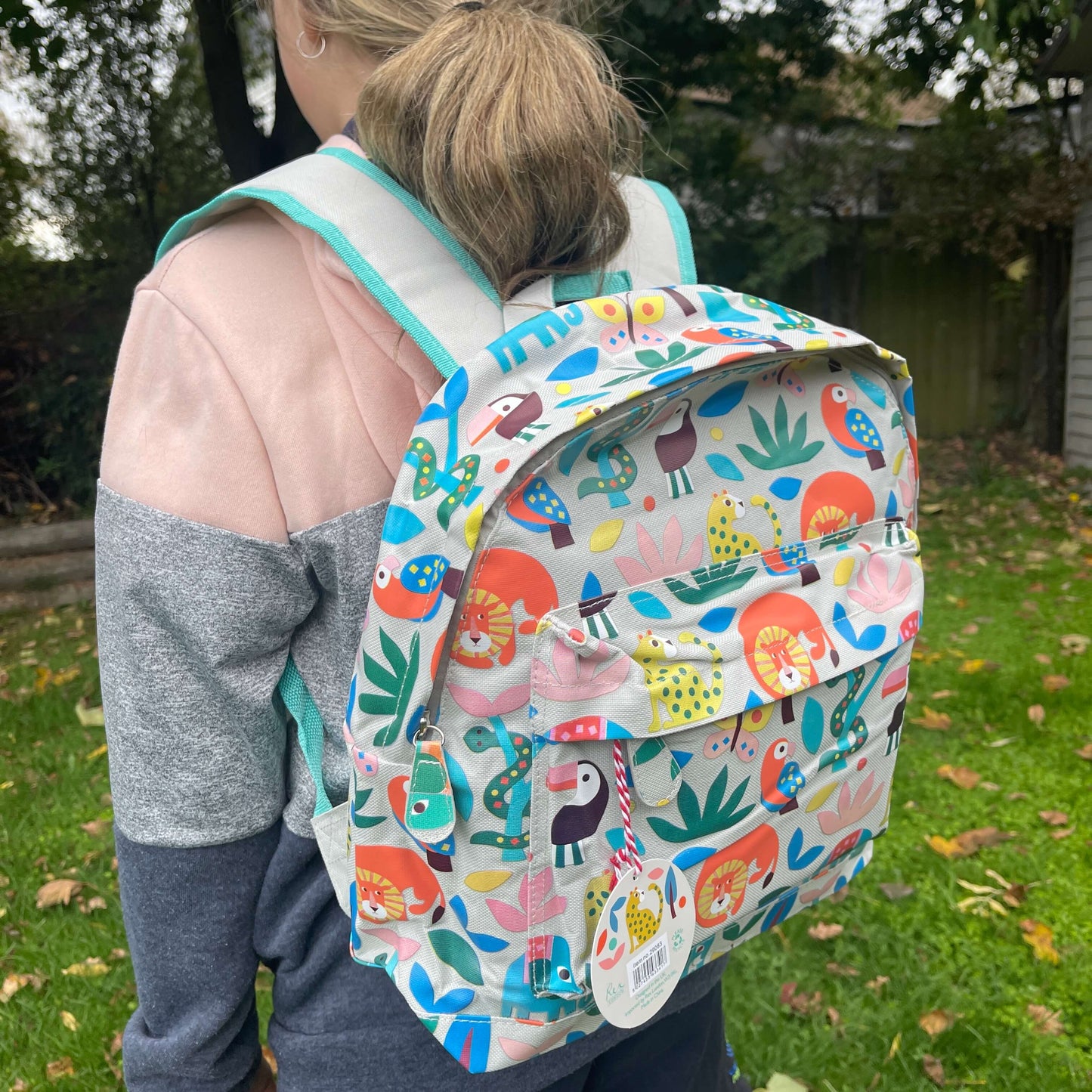 Girl wearing a backpack with bright jungle animals printed on it.