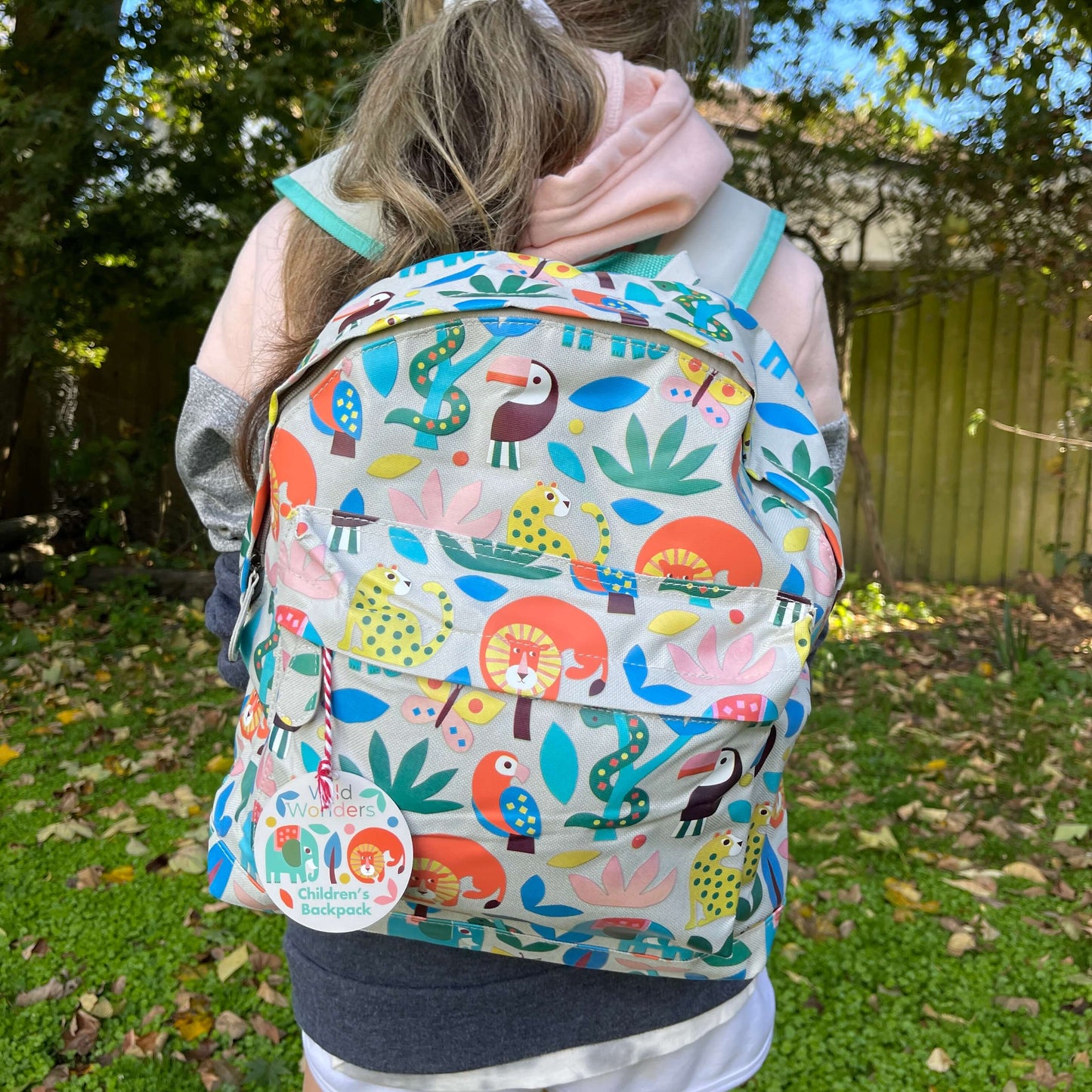 Girl wearing a backpack with bright jungle animals printed on it.