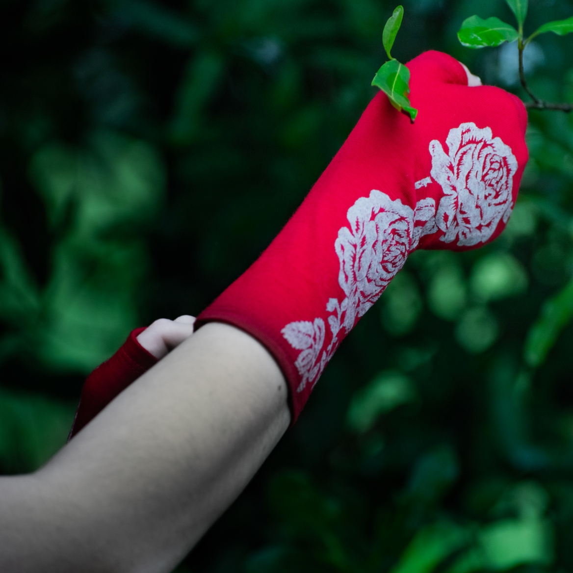 Fingerless merino gloves in red with white rose print.