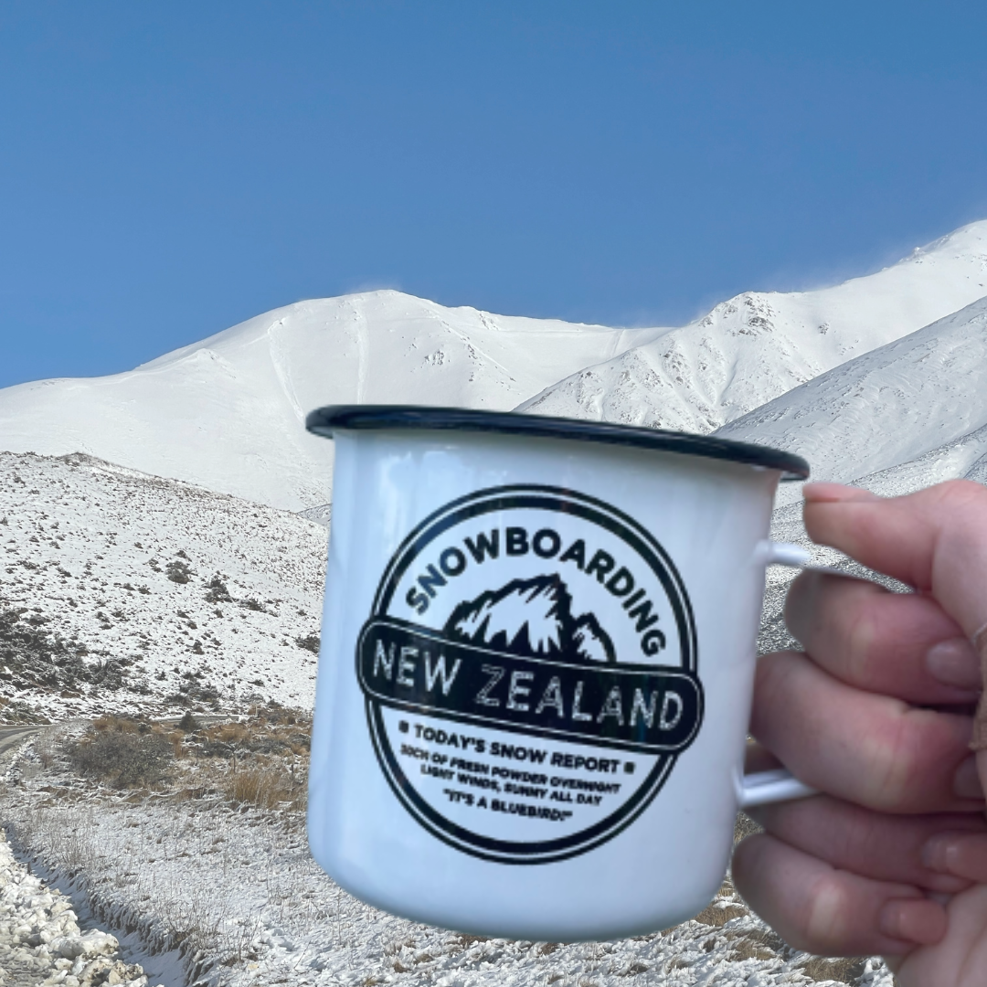 Enamel mug with snowboarding NZ on it and snowy mountains in the background.