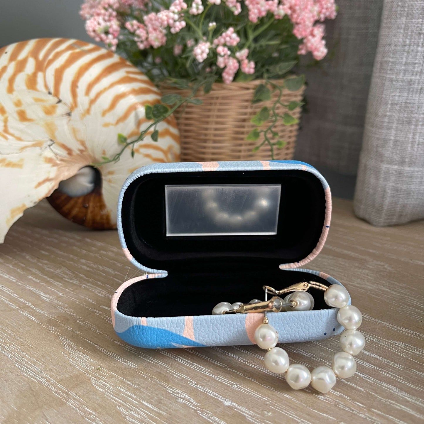 Open trinket case with mirror and pearl earrings.