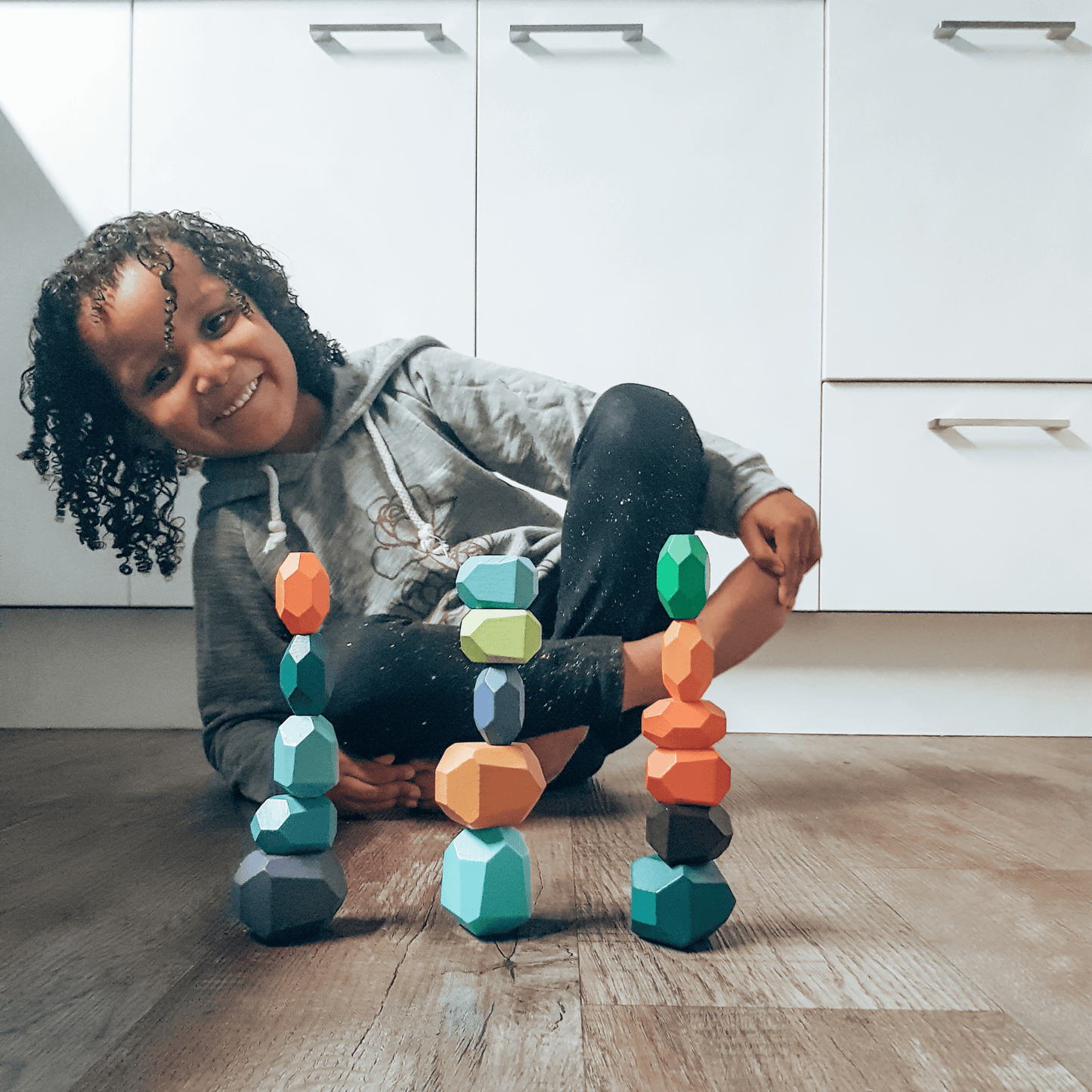 Child playing with colourful wooden balancing gems.