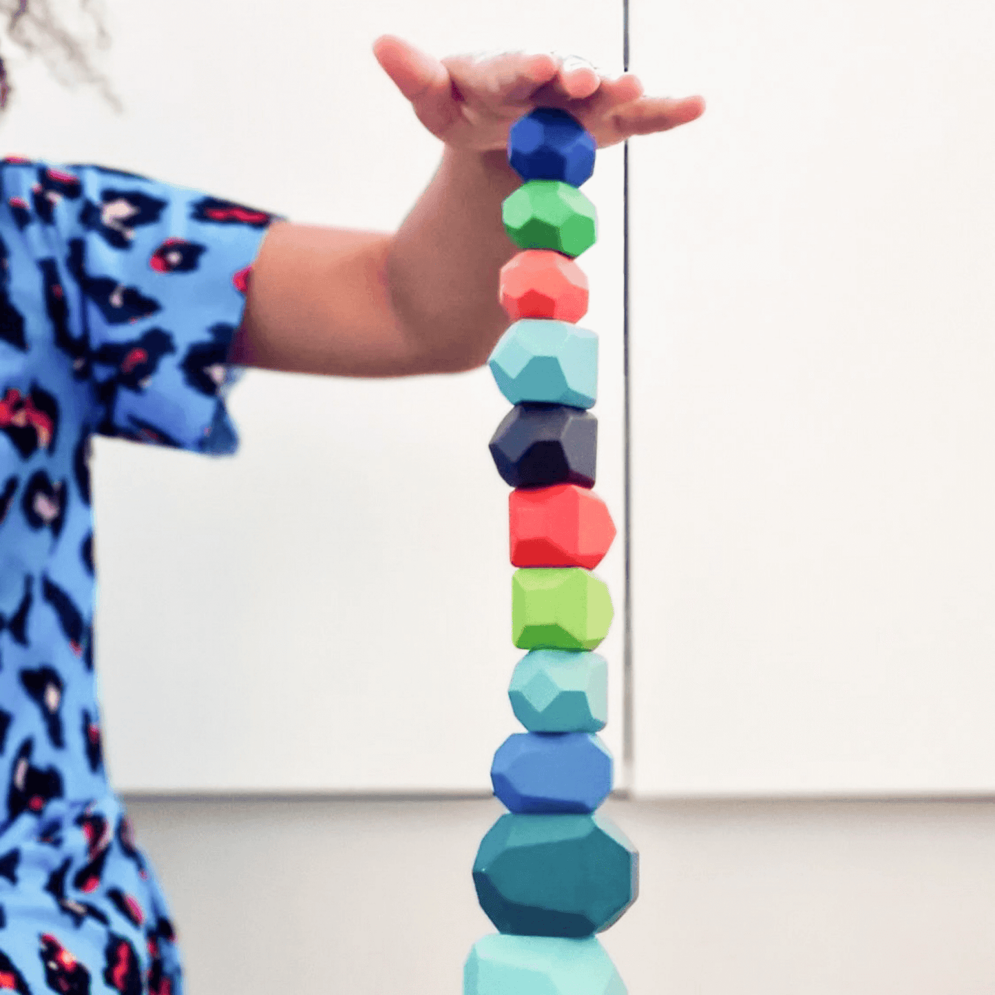 Child playing with colourful wooden balancing gems.
