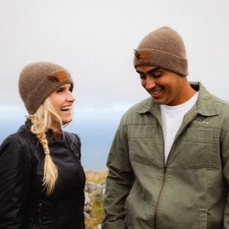 Couple wearing brown knit beanie hat with a weka feather.