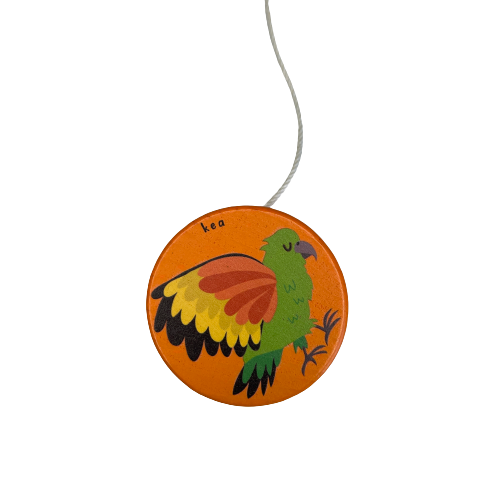 A bright orange wooden yoyo with a Kea bird painted on it.
