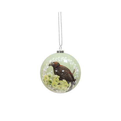 Light green Christmad bauble featuring a native NZ parrot sitting among white fllowers.